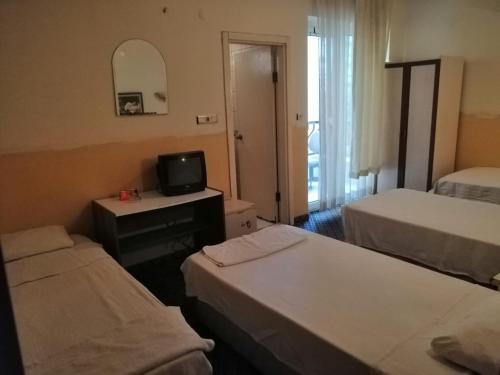 una camera d'albergo con due letti e una televisione di Kleopatra Saray Hotel a Alanya