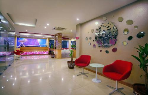 a lobby with two red chairs and a piano at favehotel Kelapa Gading in Jakarta