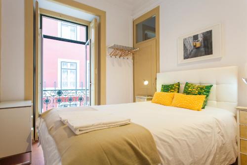 sypialnia z dużym łóżkiem z żółtymi i zielonymi poduszkami w obiekcie Coliseu by Central Hill Apartments w Lizbonie