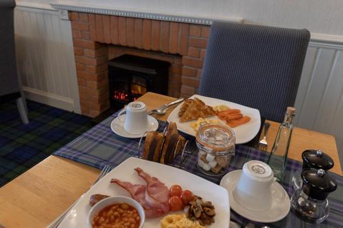 a table with two plates of food and a fireplace at Rockvilla Guest House in Lochcarron