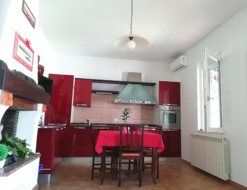 カポテッラにあるVilla Maria Apartmentsのキッチン(赤いキャビネット、テーブル、赤い椅子付)