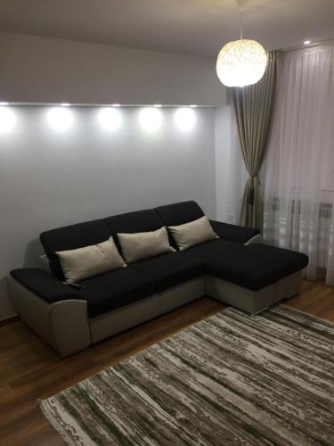 a black couch in a living room with a rug at Roby apartament in Bucharest