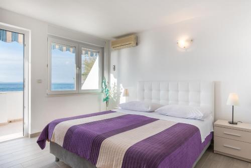 a white bedroom with a large bed and a window at Apartments Zanic on The Beach in Podstrana