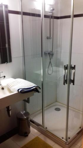 une douche avec une porte vitrée à côté d'un lavabo dans l'établissement Le vitrail CHAMBRE Équipée sans service repas, à Yvetot Bocage