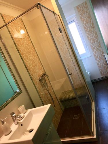 a bathroom with a sink and a shower with a mirror at Sugárút Corner Apartman in Debrecen