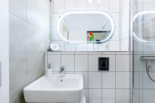 W białej łazience znajduje się umywalka i lustro. w obiekcie DR APARTMENTS w Berlinie