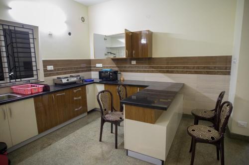 a kitchen with a counter and chairs in it at Aikya in Mangalore