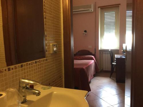 un bagno con lavandino e una camera con un letto di Hotel Ristorante Benigni a Campagnano di Roma