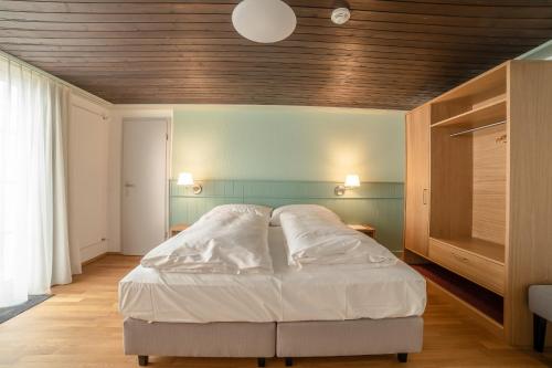 a bedroom with a white bed with a wooden ceiling at Gasthaus Friedegg in Wildhaus