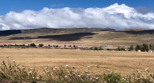 a field with a town and mountains in the background at Hostería Pionero in Cerro Castillo