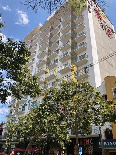 a tall white building with trees in front of it at Hotel Dorado La 70 in Medellín