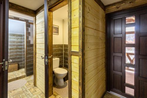 a bathroom with a toilet and wooden walls at Guest House Plai in Yaremche