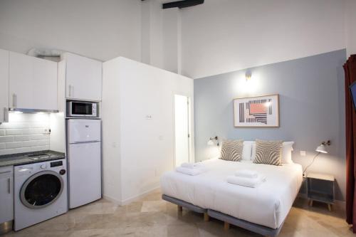 a white bedroom with a bed and a washing machine at Gran Central Suites in Madrid