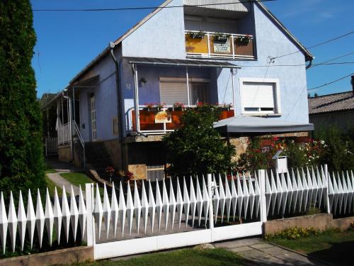 a white picket fence in front of a house at Szabó Apartmanház in Zalakaros