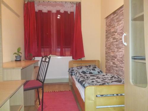 a small bedroom with a bed and a red window at Kamilla Apartman in Esztergom