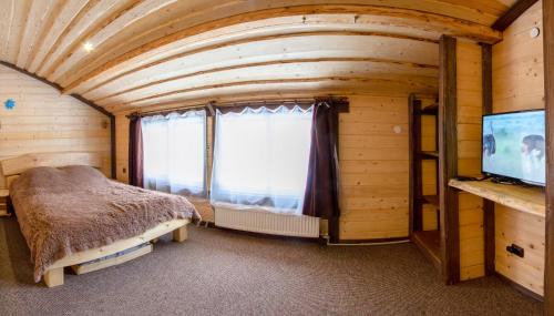 a bedroom in a log cabin with a bed and a window at Guest House Plai in Yaremche