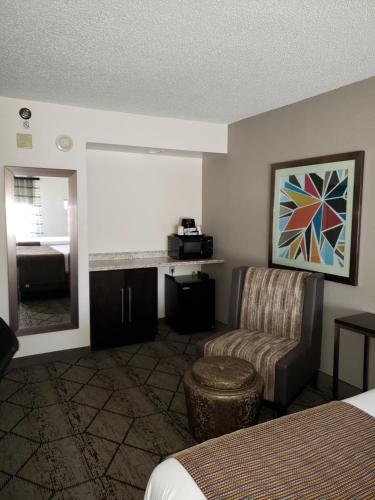 a hotel room with a bed and a chair and a mirror at Wingate by Wyndham Greenville Airport in Greenville