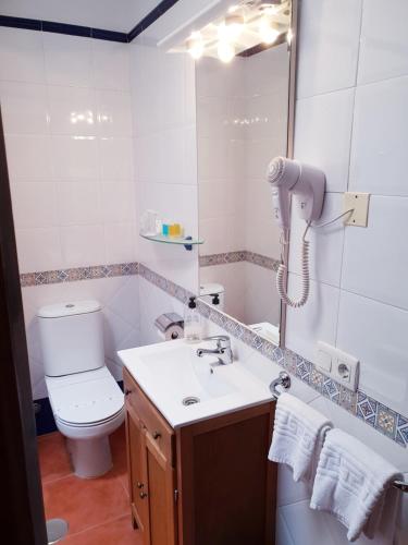 a bathroom with a sink and a toilet and a mirror at Hotel las Calas in Agua Amarga