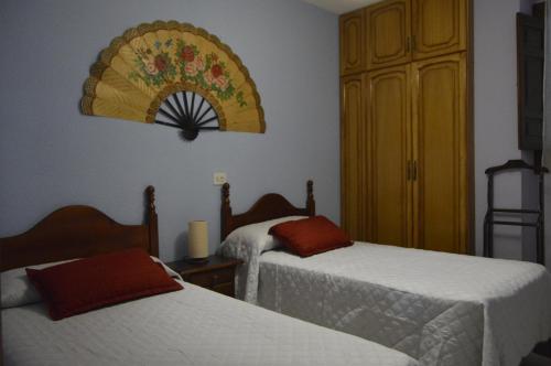 um quarto de hotel com duas camas e um relógio na parede em Casa Los Barranquillos em Lanjarón