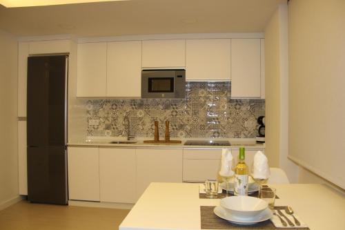 una cucina con mobili bianchi e un frigorifero nero di Romantic Loft Ventura a Tarifa