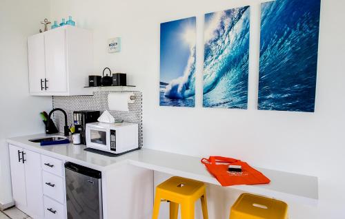 a kitchen with a counter with a microwave and yellow stools at The Beach Pad Puntas in Rincon