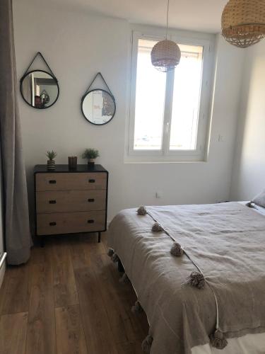 a bedroom with a bed and a dresser and two mirrors at L'Escale Sètoise in Sète