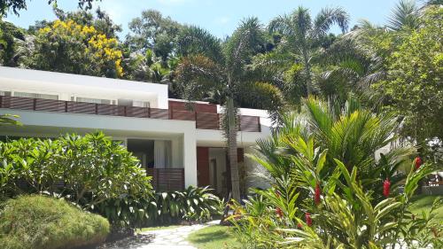a white house surrounded by trees and plants at Tropical Contemporary Suites in Paraty