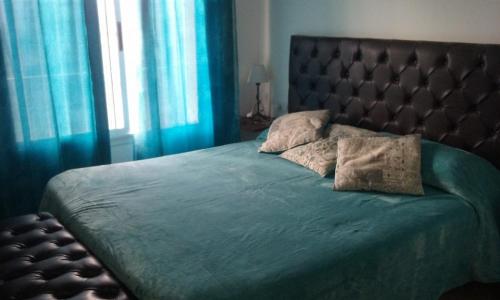 Un Buen Lugar في فيلا باركيه سيكيمان: غرفة نوم بسرير كبير مع ستائر زرقاء