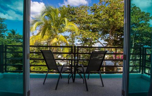 a table and chairs on a balcony with a palm tree at The Beach Pad Puntas in Rincon