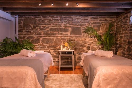 two beds in a room with a stone wall at Gothic Eves Inn and Spa Bed and Breakfast in Trumansburg
