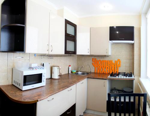 una cucina con armadi bianchi e un forno a microonde su un bancone di Уютный Тихвин апартаменты 1 микрорайон д 50 a Tichvin