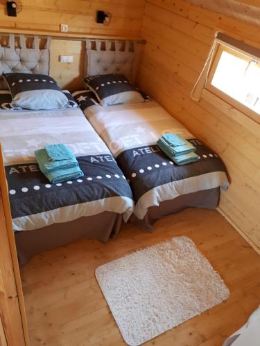 two beds in a room with a window and a rug at Gîte le châlet des milles et un chemins in Castelnou