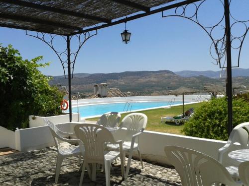 eine Terrasse mit einem Tisch, Stühlen und einem Pool in der Unterkunft Villa Turística de Priego in Priego de Córdoba