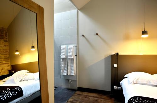a room with two beds and a mirror in a room at Aux Terrasses in Tournus