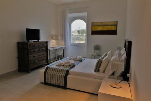 a bedroom with a bed and a desk and a television at Castello Tafuri in Portopalo