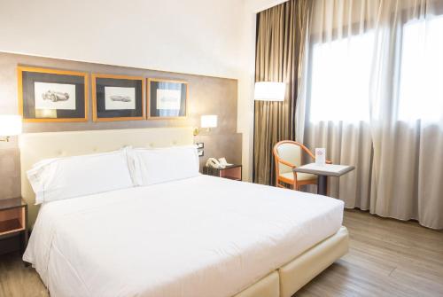 a hotel room with a large white bed and a window at Best Western Modena District in Campogalliano