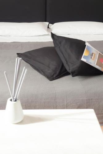a white bed with black pillows and a white table at Relais Stibbert Florence in Florence