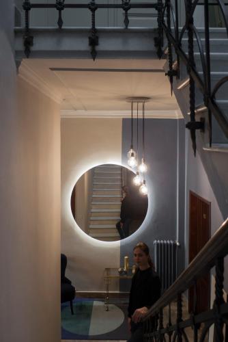a woman standing in a hallway with a round mirror at Relais Stibbert Florence in Florence