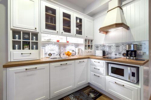 cocina blanca con armarios blancos y microondas en Rotermann Square view Apartment, en Tallin