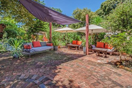 a patio with chairs and umbrellas on a brick patio at Sitatunga Guest Lodge in Johannesburg