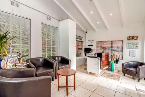 a living room with leather chairs and a table at Sitatunga Guest Lodge in Johannesburg