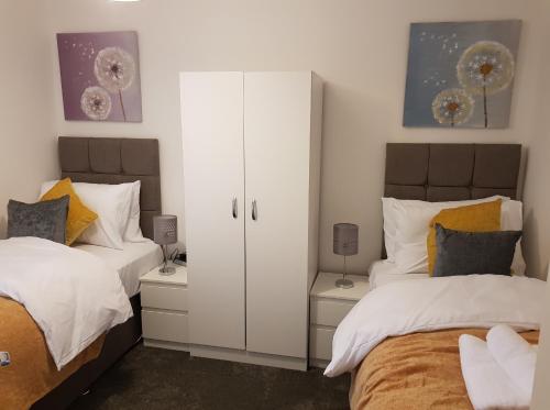 - une chambre avec 2 lits et une armoire blanche dans l'établissement Milton House - Entire 3Bed House FREE WIFI & 4 FREE PARKING Spaces Serviced Accommodation Newcastle UK, à Newcastle upon Tyne