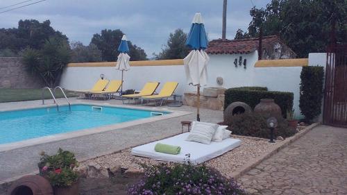 a pool with chairs and umbrellas next to a house at A Flor Da Rosa in Crato