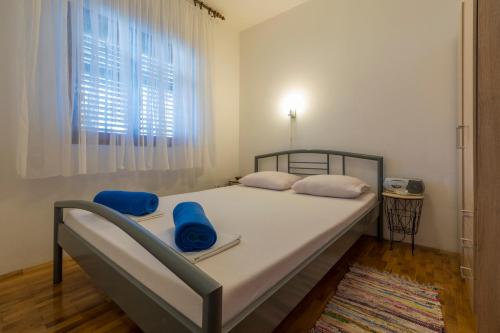 um quarto com uma cama com almofadas azuis e uma janela em Apartmani Milan em Crikvenica