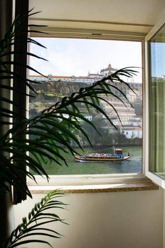 a window with a view of a boat in the water at Red House By The River in Porto
