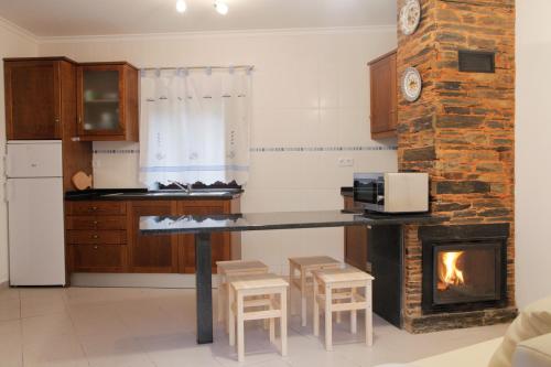 a kitchen with a table and a fireplace at Casas do Rio in Pampilhosa da Serra