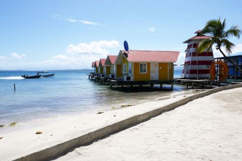 a row of houses on a beach next to the water at Faro del Colibri in Bocas del Toro