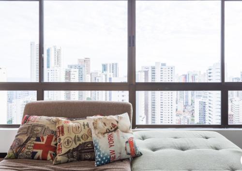 a dog sitting on a couch in front of a window at LOFT PREMIUM Boa Viagem 20 andar in Recife