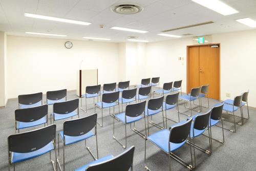 a room with a row of chairs and a door at Marroad Inn Hachioji in Hachioji