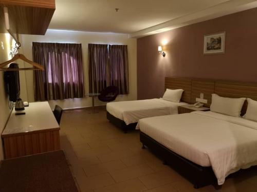 a hotel room with two beds and a desk at Grand Court Hotel in Teluk Intan